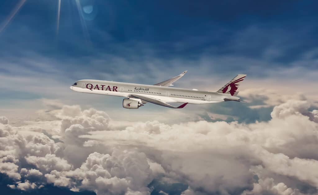 Un avión de Qatar Airways en pleno vuelo y una integrante de la tripulación, auténticas embajadoras de la compañía.