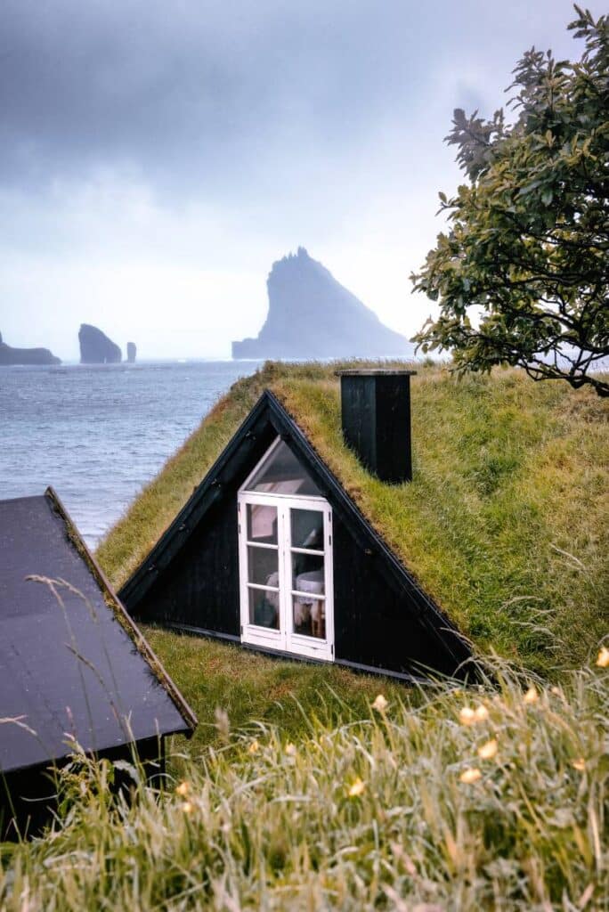 Belleza indómita: el encanto secreto de las Islas Feroe 5 Casas tradicionales con tejados de césped, con el islote de Tindhólmur al fondo.
